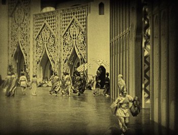Movie still from “The Thief of Bagdad” (1924), directed by Raoul Walsh – A group of people are standing in front of a building; Extreme Wide shot, High angle