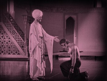 Movie still from “The Thief of Bagdad” (1924), directed by Raoul Walsh – A man kneeling down next to another man; Wide shot, High angle