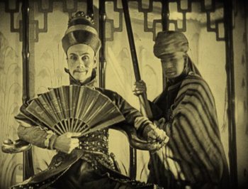 Movie still from “The Thief of Bagdad” (1924), directed by Raoul Walsh – Two men are holding a fan and a sword; Medium shot, High angle