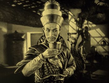 Movie still from “The Thief of Bagdad” (1924), directed by Raoul Walsh – A man in a costume holding a cup in his hands; Medium shot, Low angle