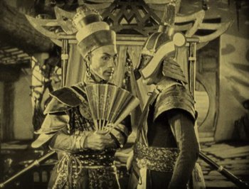 Movie still from “The Thief of Bagdad” (1924), directed by Raoul Walsh – Two men in ancient chinese garb talking to each other; Medium shot, High angle