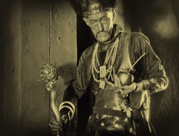 Movie still from “The Thief of Bagdad” (1924), directed by Raoul Walsh – An older man wearing a crown and holding an object in his hand; Medium shot, Low angle