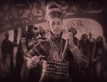 Movie still from “The Thief of Bagdad” (1924), directed by Raoul Walsh – A man dressed in a costume and holding a sword; Medium shot, High angle