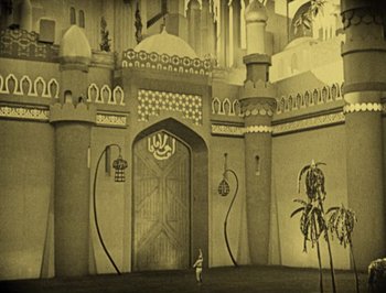 Movie still from “The Thief of Bagdad” (1924), directed by Raoul Walsh – An old photo of a castle with a person standing in front of it; Extreme Wide shot, High angle