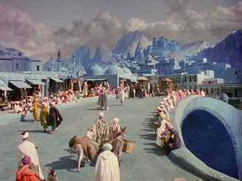 Movie still from “The Thief of Bagdad” (1940), directed by Alexander Korda – A group of people sitting on top of a cement road; Extreme Wide shot, High angle