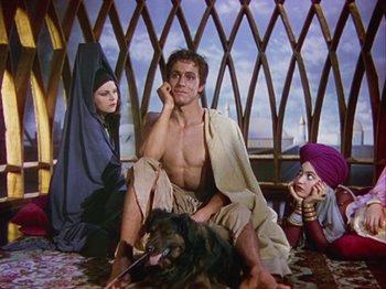 Movie still from “The Thief of Bagdad” (1940), directed by Alexander Korda – A man sitting on the ground next to two women and a dog; Medium shot, Low angle