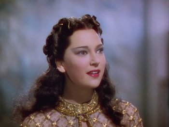 Movie still from “The Thief of Bagdad” (1940), directed by Alexander Korda – A woman with long black hair wearing a gold dress; Close Up shot, Over the shoulder angle