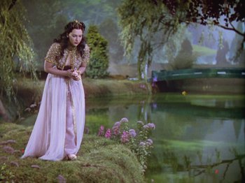 Movie still from “The Thief of Bagdad” (1940), directed by Alexander Korda – A woman dressed as a greek goddess standing next to a pond; Wide shot, High angle