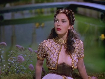 Movie still from “The Thief of Bagdad” (1940), directed by Alexander Korda – A beautiful woman in a dress sitting next to a pond; Medium shot, Over the shoulder angle