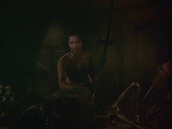 Movie still from “The Thief of Bagdad” (1940), directed by Alexander Korda – A man sitting in a dark room holding a rifle; Wide shot, Low angle