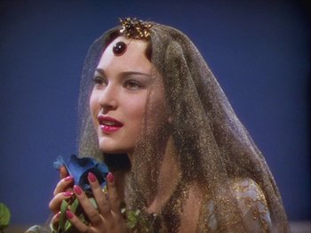 Movie still from “The Thief of Bagdad” (1940), directed by Alexander Korda – A woman in a veil holding a blue flower in her hands; Close Up shot, High angle