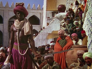 Movie still from “The Thief of Bagdad” (1940), directed by Alexander Korda – A man with a sword standing in front of a group of people; Wide shot, High angle
