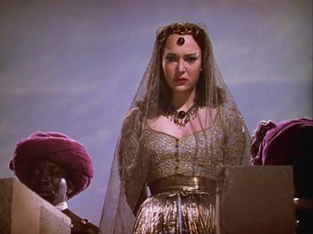 Movie still from “The Thief of Bagdad” (1940), directed by Alexander Korda – A woman wearing a veil standing in front of two other women; Medium shot, Over the shoulder angle