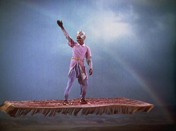 Movie still from “The Thief of Bagdad” (1940), directed by Alexander Korda – A man in a costume standing on top of a rug; Wide shot, High angle