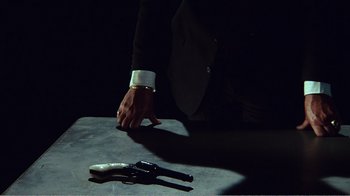 Movie still from “The Thin Blue Line” (1988), directed by Errol Morris – A man in a white shirt and black jacket holding a gun; Extreme Close Up shot, High angle