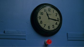 Movie still from “The Thin Blue Line” (1988), directed by Errol Morris – A clock on the side of a blue wall; Extreme Close Up shot, Overhead angle