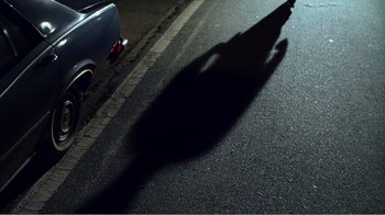 Movie still from “The Thin Blue Line” (1988), directed by Errol Morris – A shadow of a person on the street; Extreme Wide shot, High angle