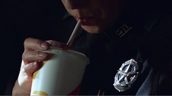 Movie still from “The Thin Blue Line” (1988), directed by Errol Morris – A police officer is drinking from a cup; Close Up shot, Low angle