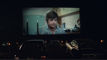 Movie still from “The Thin Blue Line” (1988), directed by Errol Morris – A man in plaid shirt sitting in front of a screen; Medium shot, Over the shoulder angle