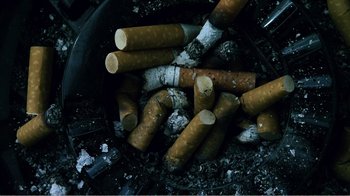Movie still from “The Thin Blue Line” (1988), directed by Errol Morris – A pile of cigarette butts sitting on top of a pile of ashes; Extreme Close Up shot, Overhead angle