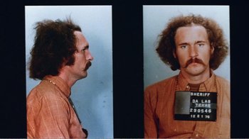 Movie still from “The Thin Blue Line” (1988), directed by Errol Morris – A mug shot of a man with a beard and mustache; Close Up shot, Low angle
