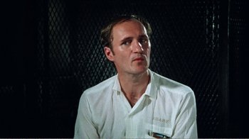 Movie still from “The Thin Blue Line” (1988), directed by Errol Morris – A man wearing a white shirt is sitting in front of a black background; Close Up shot, Over the shoulder angle