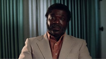 Movie still from “The Thin Blue Line” (1988), directed by Errol Morris – A man in a tan jacket and a brown shirt; Close Up shot, Low angle