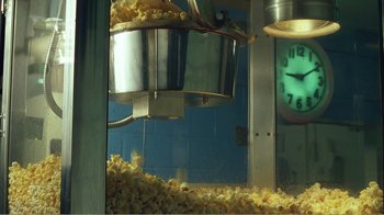 Movie still from “The Thin Blue Line” (1988), directed by Errol Morris – Popcorn is being poured into a large container; Medium shot, Low angle