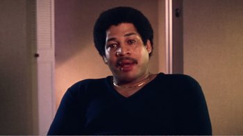 Movie still from “The Thin Blue Line” (1988), directed by Errol Morris – A man in a black shirt is looking at the camera; Close Up shot, Low angle