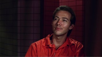 Movie still from “The Thin Blue Line” (1988), directed by Errol Morris – A man in a red shirt is looking to his left; Close Up shot, Low angle