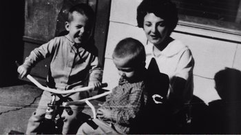 Movie still from “The Thin Blue Line” (1988), directed by Errol Morris – An old photo of a woman and two boys; Medium shot, High angle