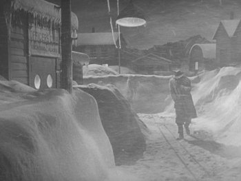 Movie still from “The Thing from Another World” (1951), directed by Howard Hawks – A man is walking in the snow near a building; Extreme Wide shot, High angle