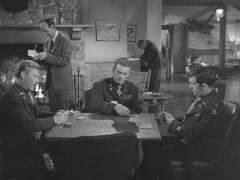 Movie still from “The Thing from Another World” (1951), directed by Howard Hawks – A black and white photo of men playing cards; Wide shot, High angle