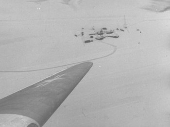 Movie still from “The Thing from Another World” (1951), directed by Howard Hawks – An aerial view of an airfield with a plane flying in the background; Extreme Wide shot, High angle