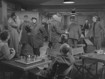 Movie still from “The Thing from Another World” (1951), directed by Howard Hawks – A black and white photo of a group of people in a room; Wide shot, High angle