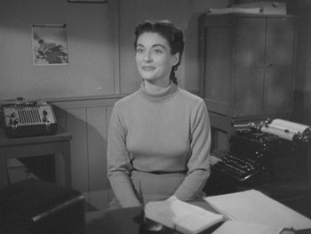 Movie still from “The Thing from Another World” (1951), directed by Howard Hawks – An old photo of a woman sitting at a desk in front of a typewriter; Medium shot, High angle