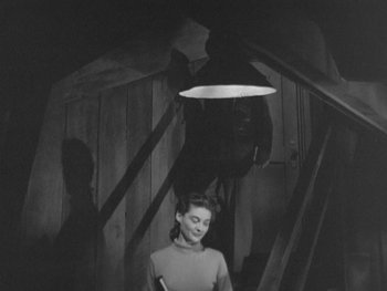 Movie still from “The Thing from Another World” (1951), directed by Howard Hawks – An old photo of a woman standing on a set of stairs; Medium shot, High angle