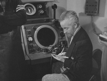 Movie still from “The Thing from Another World” (1951), directed by Howard Hawks – An older man sitting in front of an old radio; Medium shot, High angle