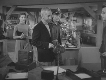 Movie still from “The Thing from Another World” (1951), directed by Howard Hawks – A black - and - white photo of a man and a woman in an office; Medium shot, High angle