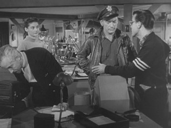 Movie still from “The Thing from Another World” (1951), directed by Howard Hawks – A group of men standing around a table; Medium shot, Over the shoulder angle