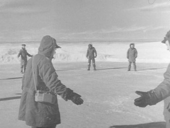 Movie still from “The Thing from Another World” (1951), directed by Howard Hawks – A black and white photo of a group of people standing in the snow; Wide shot, High angle