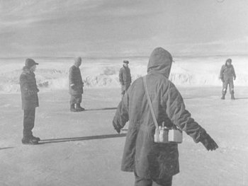 Movie still from “The Thing from Another World” (1951), directed by Howard Hawks – A black and white photo of a group of people standing in the snow; Wide shot, High angle