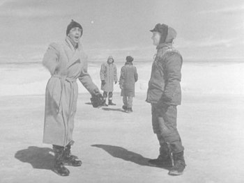 Movie still from “The Thing from Another World” (1951), directed by Howard Hawks – A group of people standing on top of a snow covered slope; Wide shot, Over the shoulder angle