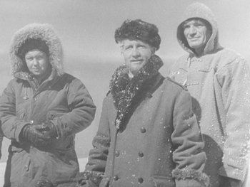 Movie still from “The Thing from Another World” (1951), directed by Howard Hawks – A group of men standing next to each other in the snow; Medium shot, High angle