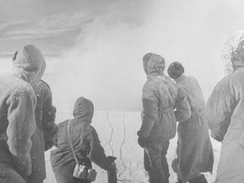 Movie still from “The Thing from Another World” (1951), directed by Howard Hawks – A black and white photo of a group of people standing in the snow; Medium shot, High angle
