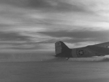 Movie still from “The Thing from Another World” (1951), directed by Howard Hawks – An airplane is flying in the sky on a cloudy day; Extreme Wide shot, Low angle