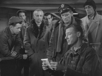 Movie still from “The Thing from Another World” (1951), directed by Howard Hawks – A group of men standing next to each other in a room; Medium shot, High angle