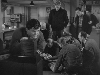 Movie still from “The Thing from Another World” (1951), directed by Howard Hawks – A group of men sitting around a room together; Medium shot, High angle