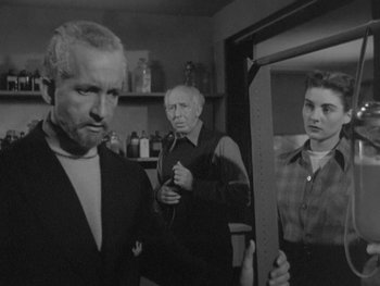 Movie still from “The Thing from Another World” (1951), directed by Howard Hawks – A group of people standing next to each other in a room; Medium shot, Over the shoulder angle