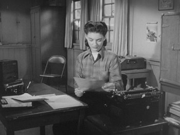 Movie still from “The Thing from Another World” (1951), directed by Howard Hawks – A woman sitting at a table with a typewriter; Medium shot, High angle